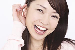 耳に手を当てる女性