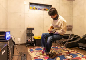 ギターはB'zのギタリスト松本孝弘さん愛用のギブソン社のレスポール。スピーカー側は、ヒュースアンドケトナーとマーシャルの組み合わせ。顔は稲葉さん似
