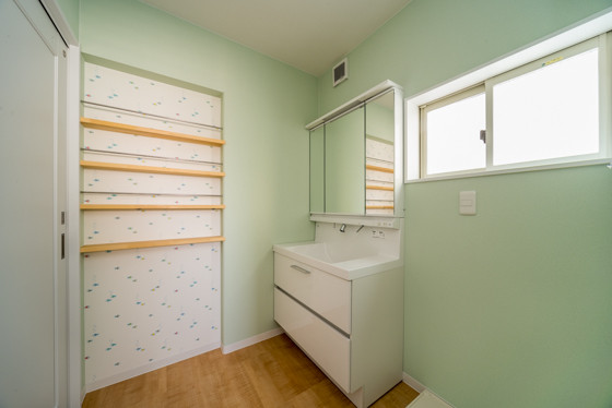 爽やかなミントグリーンの壁紙に包まれた洗面室 注文住宅の施工実例
